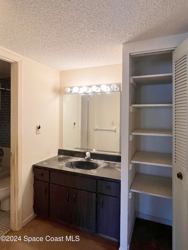 bathroom featuring vanity, a textured ceiling, and toilet