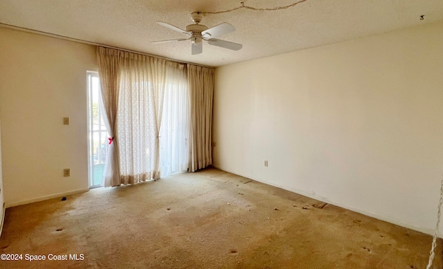 unfurnished room featuring ceiling fan, light colored carpet, and a textured ceiling