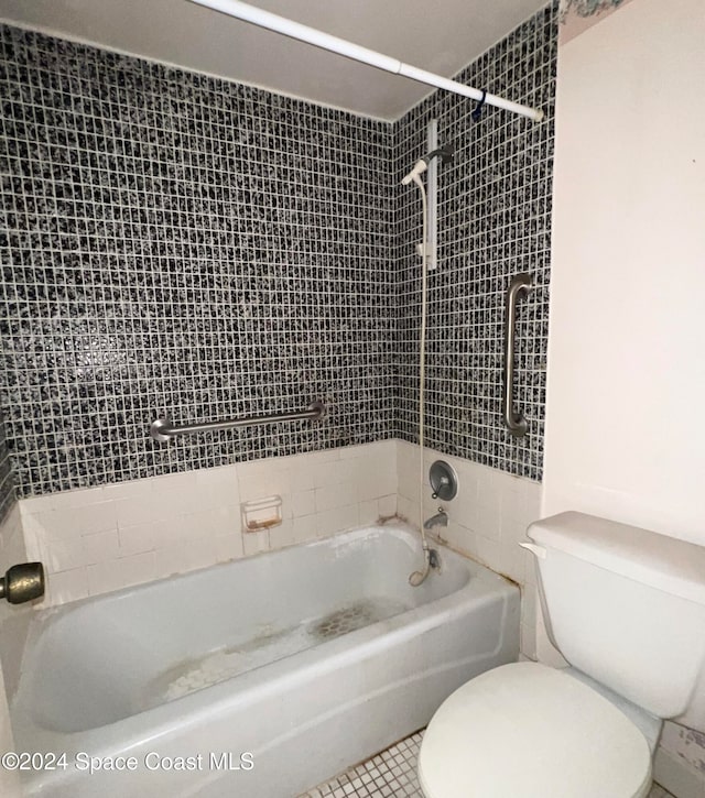 bathroom with tile patterned floors, tiled shower / bath combo, and toilet