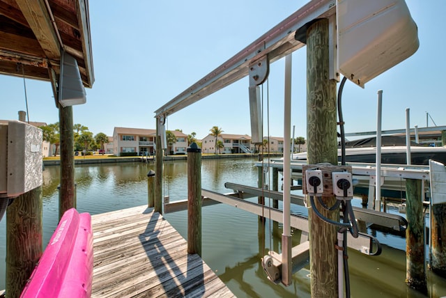dock area featuring boat lift, a water view, and a residential view