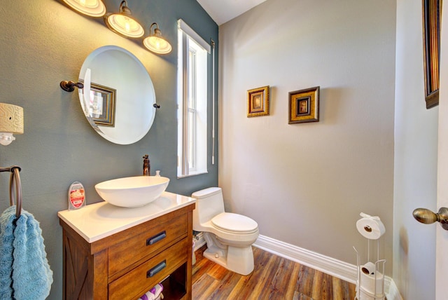 bathroom featuring plenty of natural light, toilet, vanity, and wood finished floors