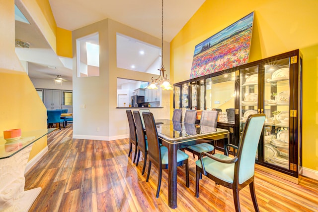 dining space featuring a chandelier, high vaulted ceiling, and wood-type flooring