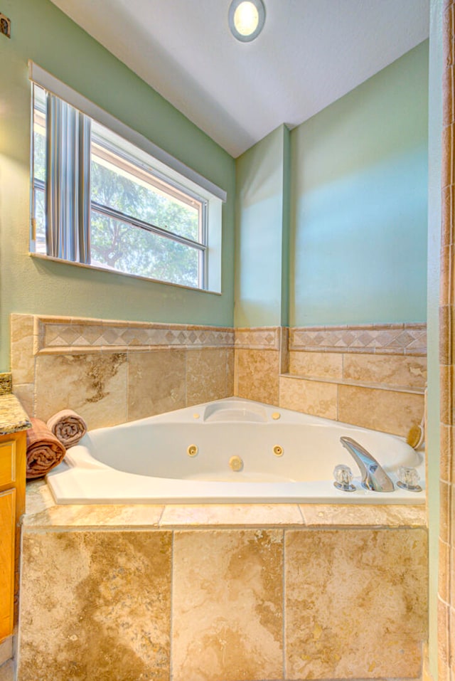 bathroom with vanity and tiled tub