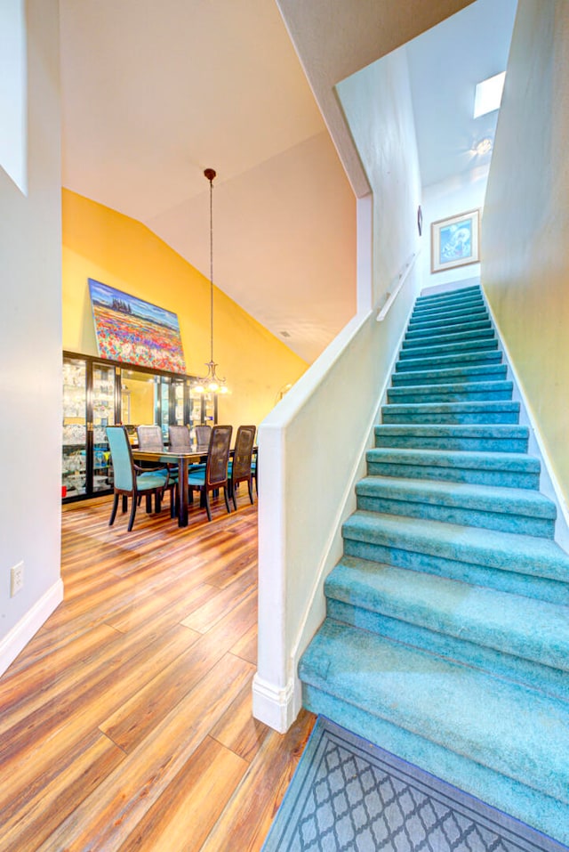 stairs with hardwood / wood-style flooring and vaulted ceiling