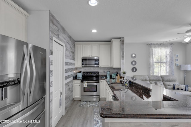 kitchen with dark stone counters, sink, light hardwood / wood-style flooring, appliances with stainless steel finishes, and white cabinetry