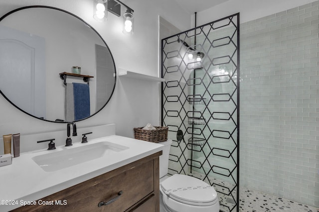 bathroom featuring vanity, toilet, and a tile shower