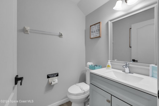 bathroom featuring vanity, vaulted ceiling, and toilet