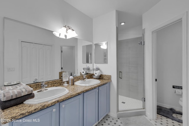 bathroom with tile patterned flooring, vanity, a shower with shower door, and toilet