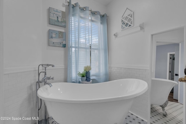 bathroom with tile patterned floors, a bath, and tile walls