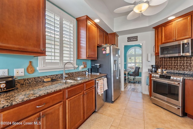 kitchen featuring ceiling fan, sink, stainless steel appliances, dark stone counters, and light tile patterned floors