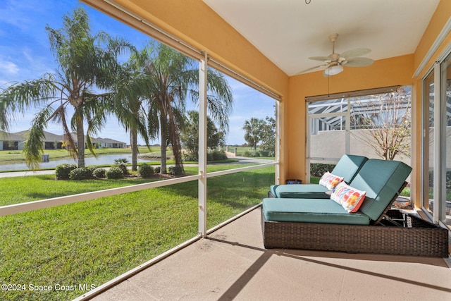 sunroom featuring ceiling fan and a water view