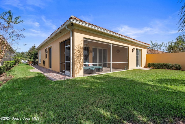 rear view of house featuring a lawn and a sunroom