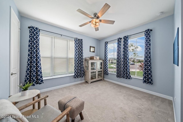 sitting room featuring a wealth of natural light, ceiling fan, and light carpet