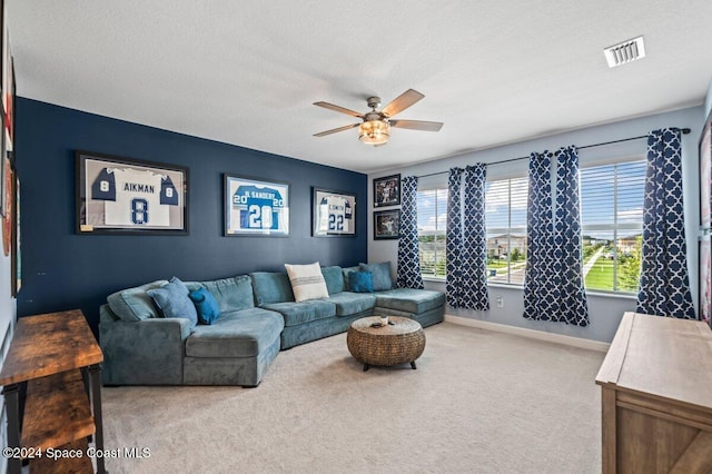 living room featuring ceiling fan, light colored carpet, and a textured ceiling