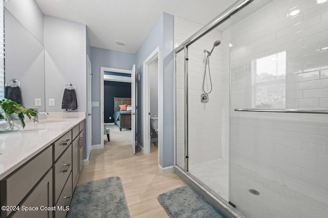 bathroom with toilet, a shower with door, vanity, and hardwood / wood-style flooring