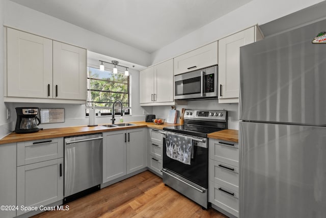 kitchen featuring white cabinets, light hardwood / wood-style floors, appliances with stainless steel finishes, and wooden counters