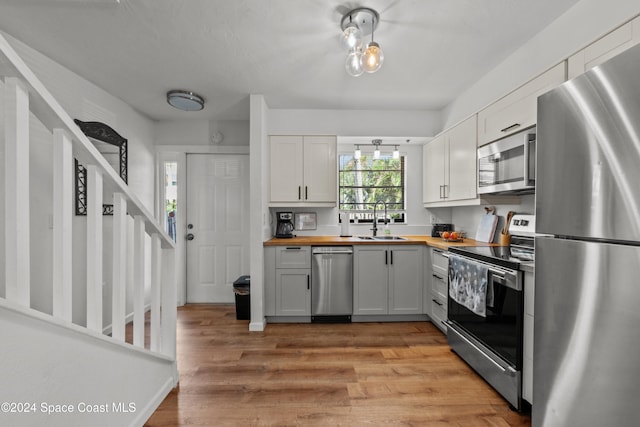 kitchen featuring appliances with stainless steel finishes, butcher block countertops, white cabinetry, and sink