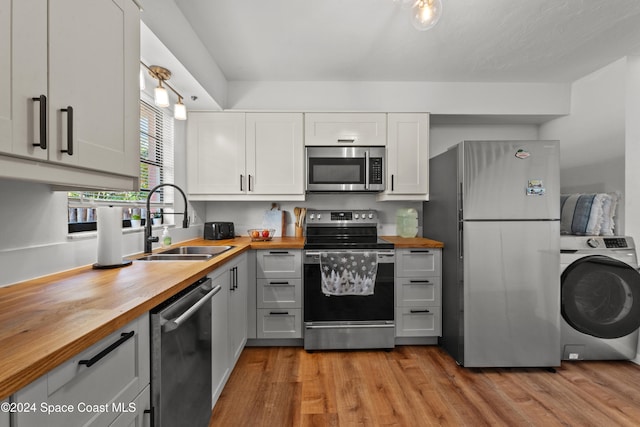 kitchen featuring white cabinets, wood counters, washer / dryer, and appliances with stainless steel finishes