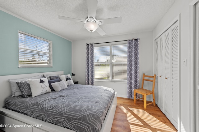 bedroom featuring a textured ceiling, light hardwood / wood-style floors, a closet, and ceiling fan