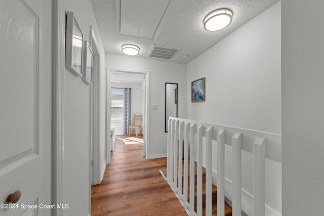 corridor featuring a textured ceiling and light wood-type flooring