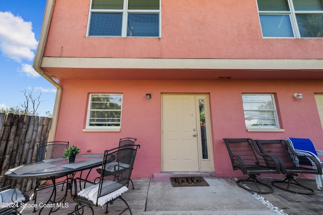 13433 Heald Ln Unit 1, Fort Myers, FL 33908 - view of exterior entry with stucco siding, outdoor dining space, and a patio