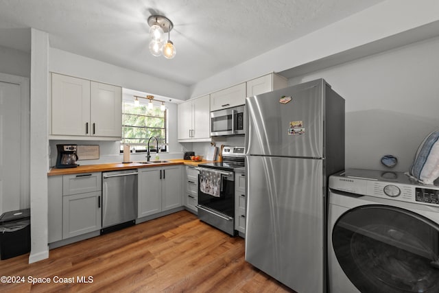 13433 Heald Ln Unit 1, Fort Myers, FL 33908 - kitchen featuring butcher block countertops, washer / clothes dryer, appliances with stainless steel finishes, light wood-type flooring, and white cabinets