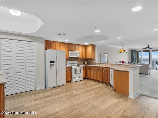 kitchen with kitchen peninsula, light hardwood / wood-style flooring, pendant lighting, and white appliances