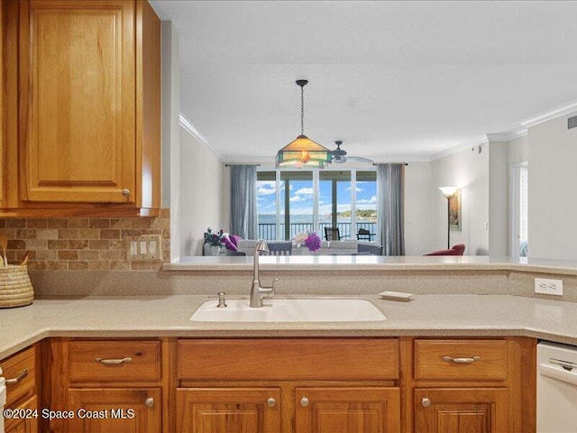 kitchen featuring white dishwasher, sink, ornamental molding, tasteful backsplash, and decorative light fixtures