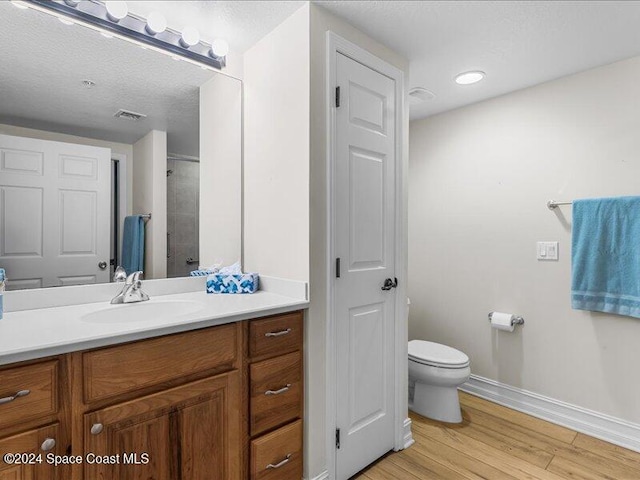 bathroom with wood-type flooring, vanity, a textured ceiling, and toilet