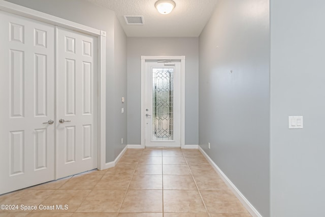 entryway with light tile patterned floors and a textured ceiling