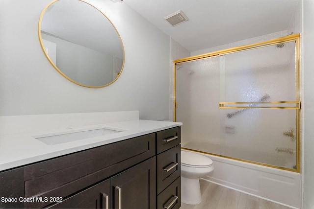 full bathroom with hardwood / wood-style floors, vanity, toilet, and bath / shower combo with glass door