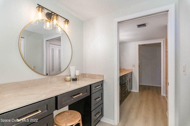 bathroom with hardwood / wood-style flooring, vanity, and a textured ceiling