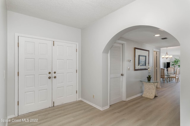 foyer featuring a notable chandelier, light hardwood / wood-style floors, and a textured ceiling