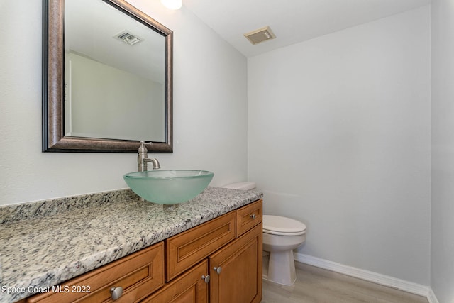 bathroom featuring vanity, wood-type flooring, and toilet