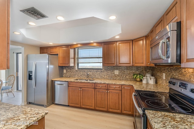 kitchen with a raised ceiling, sink, light hardwood / wood-style floors, and appliances with stainless steel finishes