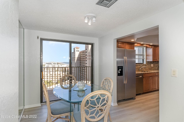 dining space with a textured ceiling, light hardwood / wood-style floors, and sink