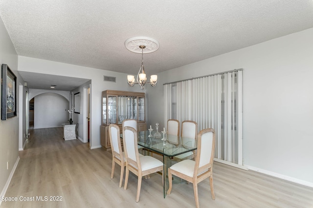 dining space featuring a textured ceiling, an inviting chandelier, and light hardwood / wood-style flooring