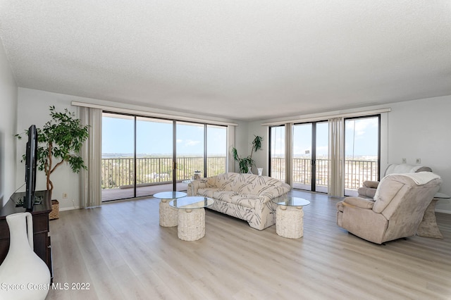 living room with light hardwood / wood-style flooring, expansive windows, and a textured ceiling