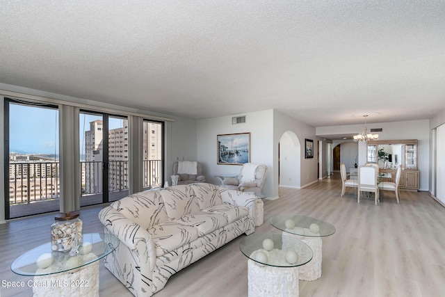 living room featuring light hardwood / wood-style flooring, a chandelier, and a textured ceiling