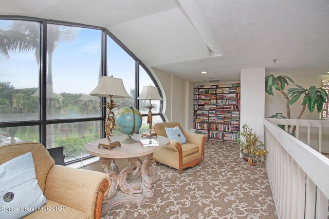 living area with carpet, floor to ceiling windows, a water view, and a baseboard heating unit