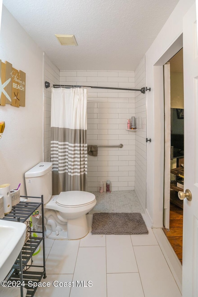 bathroom with a shower with shower curtain, a textured ceiling, toilet, and tile patterned flooring