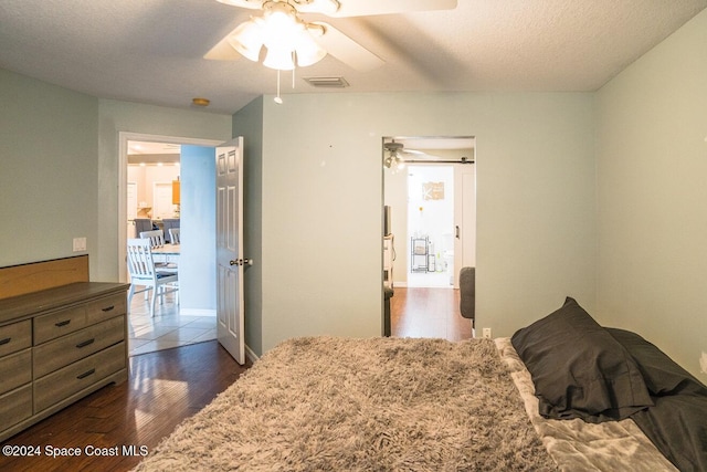 bedroom with a textured ceiling, dark hardwood / wood-style floors, and ceiling fan