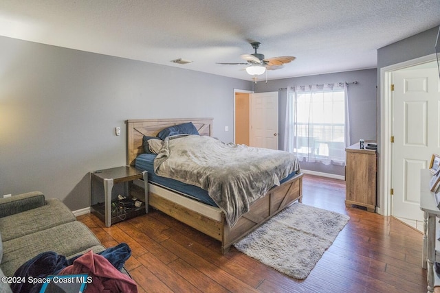 bedroom featuring a textured ceiling, dark hardwood / wood-style floors, and ceiling fan