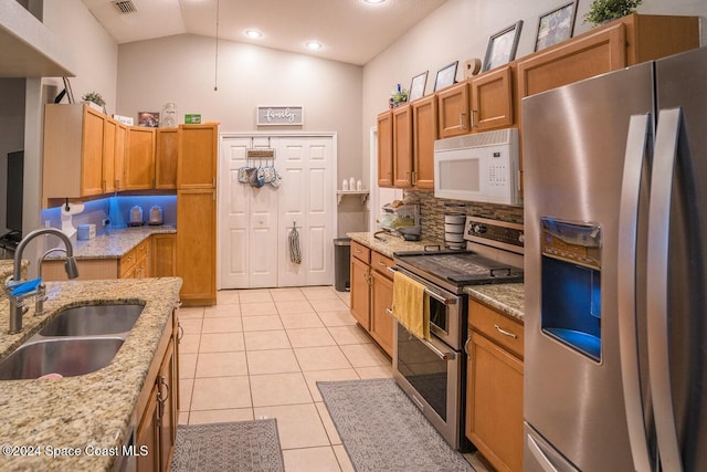 kitchen with tasteful backsplash, light stone counters, stainless steel appliances, sink, and light tile patterned floors