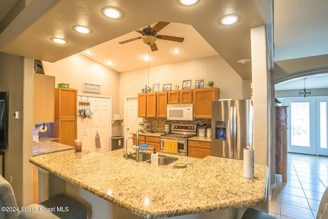 kitchen featuring kitchen peninsula, stainless steel appliances, ceiling fan, and lofted ceiling