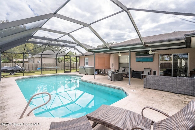 view of pool with outdoor lounge area, a patio, glass enclosure, and ceiling fan