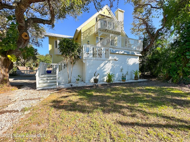 5875 Riverside Dr, Melbourne Beach, FL 32951 - rear view of property featuring a balcony, a lawn, and stairway