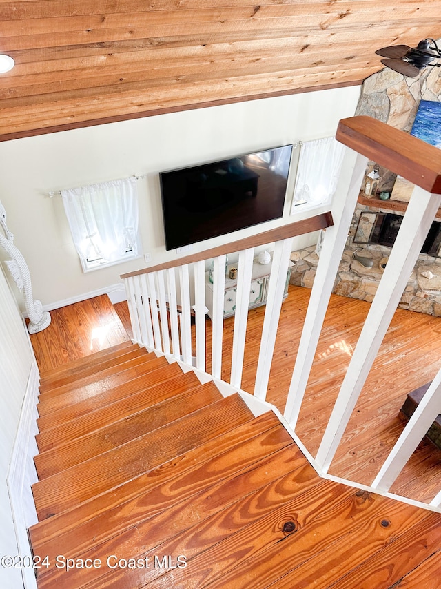 stairs with wood ceiling, wood-type flooring, and lofted ceiling