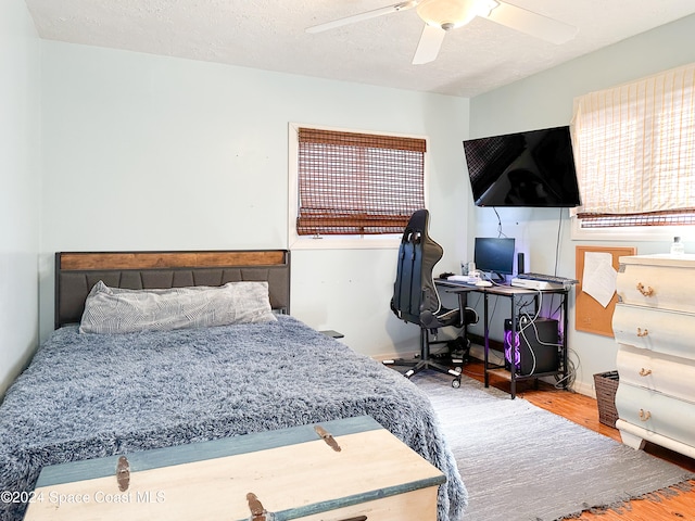 bedroom featuring hardwood / wood-style flooring, ceiling fan, and a textured ceiling