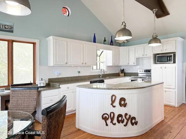5875 Riverside Dr, Melbourne Beach, FL 32951 - kitchen with appliances with stainless steel finishes, white cabinetry, high vaulted ceiling, a center island, and a sink